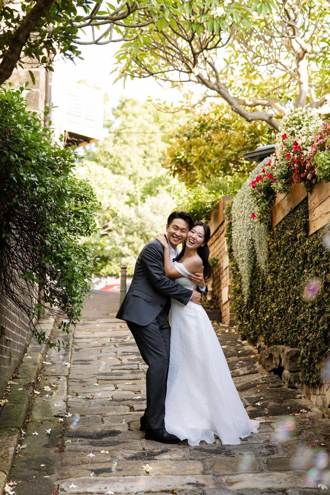 Frank and Seoyun laughing together on a garden laneway
