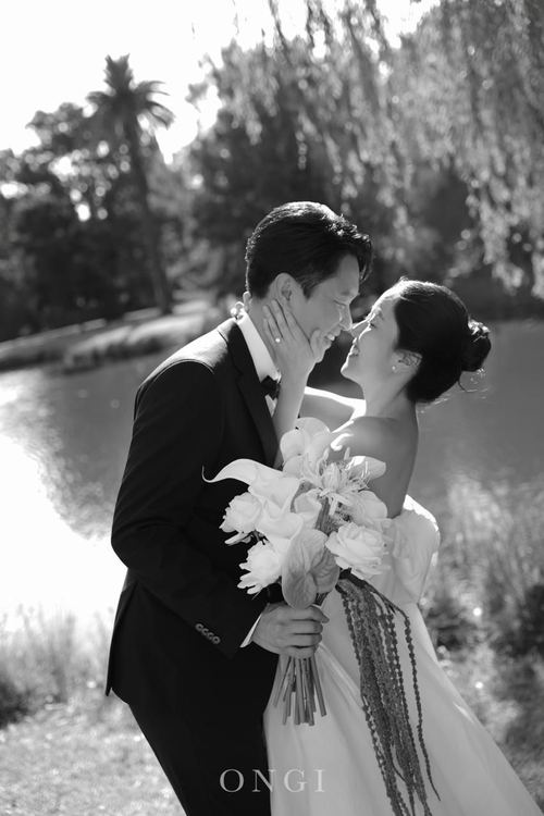 Frank and Seoyun forehead to forehead by the lake, in black and white