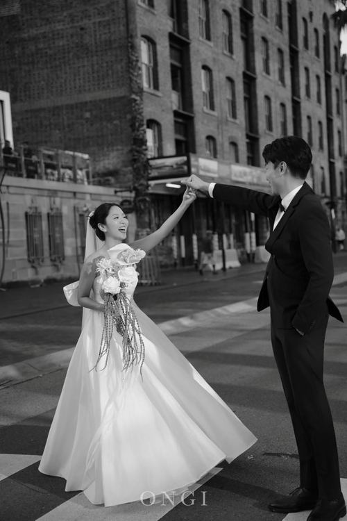 Frank twirling Seoyun on a city crossing, in black and white